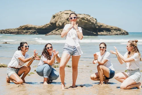 Groupe de filles souriantes en EVJF sur la plage de Biarritz posant devant l ocean pendant un city game evjf biarritz