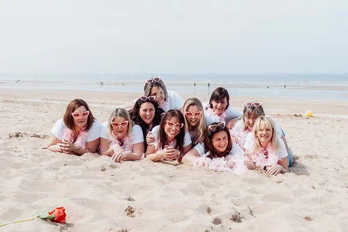 Groupe de femmes allongées sur le sable souriantes lors d’un city game EVJF à Cabourg sur la plage.