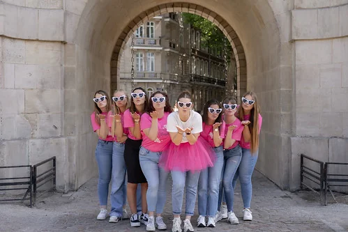 groupe de filles en tee shirts roses pose sous une arcade avec la mariee au centre