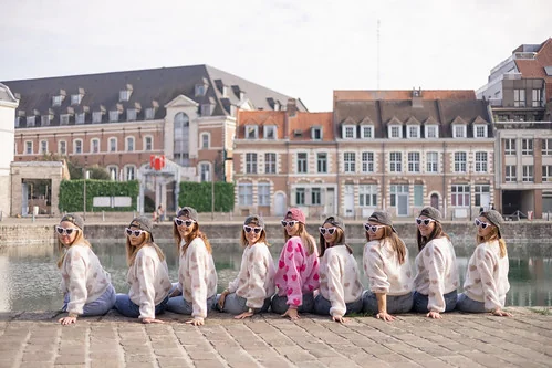 groupe de filles assises au bord de l eau pendant un city game evjf lille avec vue sur les batiments du vieux lille