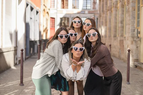 groupe de filles posant dans une rue avec des lunettes en forme de cœur