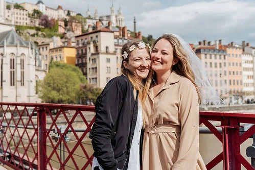 deux amies souriantes lors d un city game evjf lyon sur une passerelle avec vue sur le vieux lyon