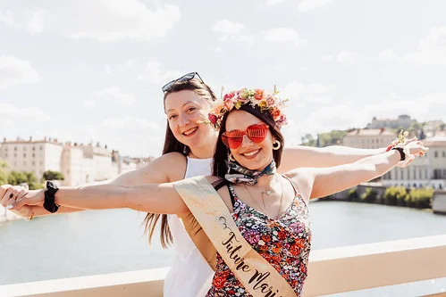 future mariee souriante avec une amie bras ouverts au bord de la saone