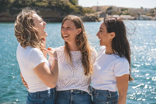 trois copines rient ensemble en bord de mer