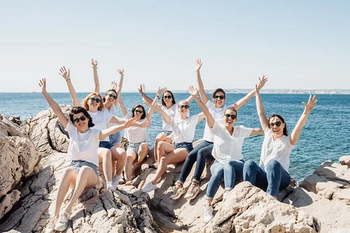 groupe de copines levant les bras sur des rochers en bord de mer lors d un city game evjf marseille