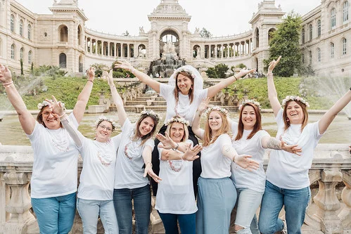 groupe de copines joyeuses levant les bras devant le palais longchamp