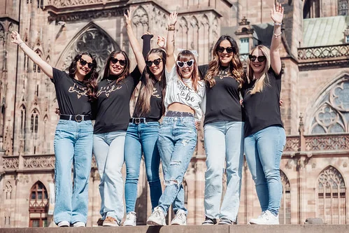 groupe de femmes souriantes participant à un city game evjf à strasbourg devant la cathédrale