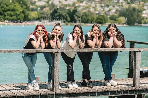 Groupe de filles appuyées sur un ponton en riant face au lac pendant un clip video evjf annecy
