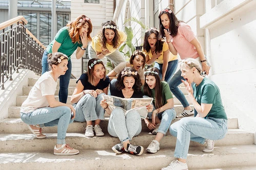 groupe de filles evjf regardant une carte style clip video evjf lyon assises sur des marches