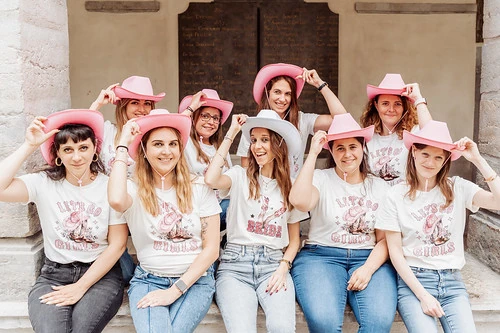 groupe de filles evjf avec chapeaux roses pose assise souriante