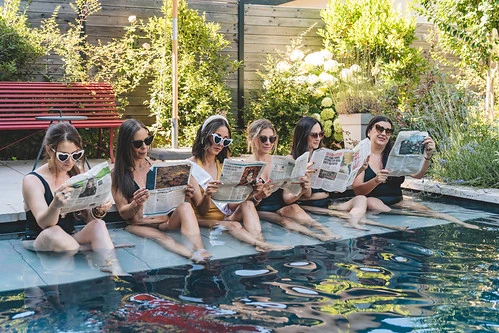 groupe de filles evjf lisant des journaux au bord d une piscine