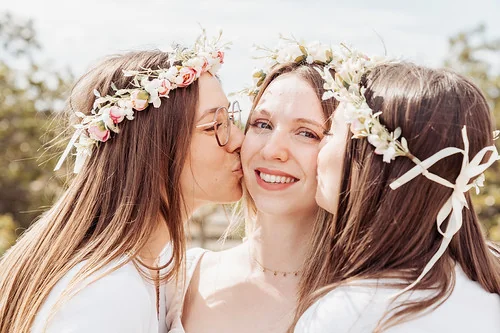 copines faisant un bisou à la future mariée avec couronnes de fleurs et sourire