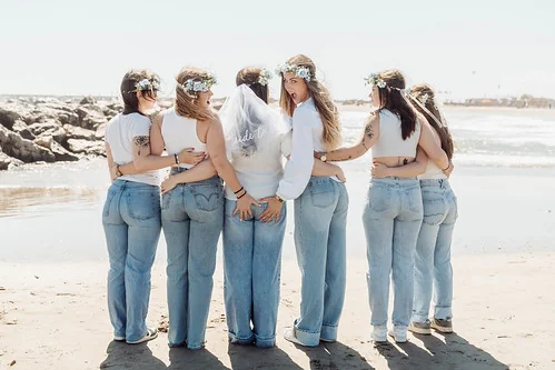 10 bonnes raisons de faire un evjf à montpellier : copines de dos sur la plage en jean et couronnes de fleurs avec geste complice