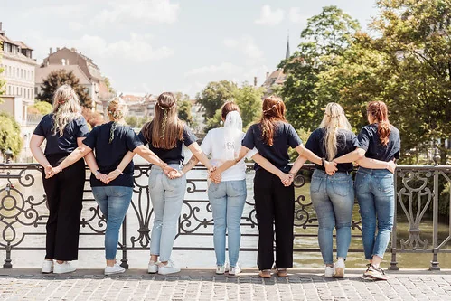groupe de femmes de dos tenant la future mariée par la taille sur un pont à strasbourg pendant un jeu de piste evjf paranormal