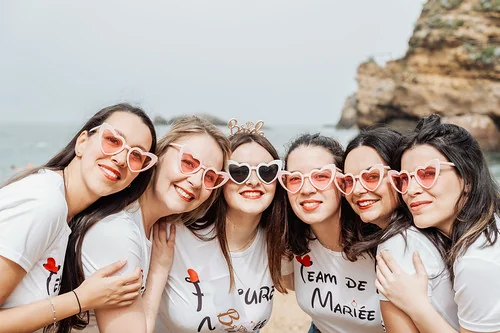 groupe de femmes portant des lunettes en forme de coeur souriant sur la plage lors d un jeu de piste evjf paranormal a biarritz
