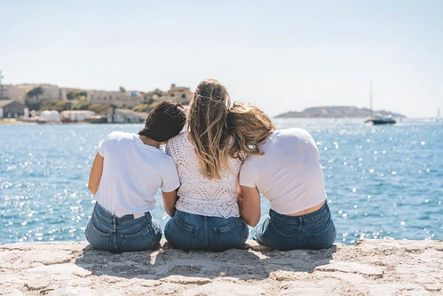 Trois amies assises face à la mer à Marseille, complices et détendues