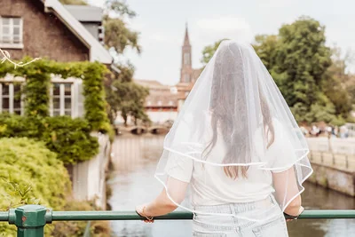 femme de dos portant un voile de mariée devant les canaux et la cathédrale de strasbourg pendant un jeu de piste evjf paranormal
