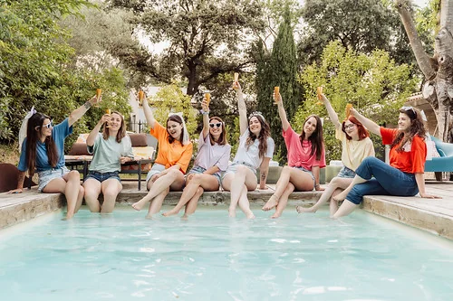 groupe d amies célébrant  en levant leurs verres autour d une piscine