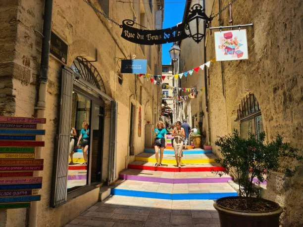 ruelle colorée du centre historique de montpellier avec des passants et des enseignes d escape game