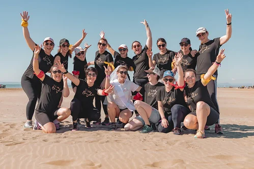 groupe de femmes souriantes célébrant un evjf sur la plage à montpellier lors d’une activité escape game