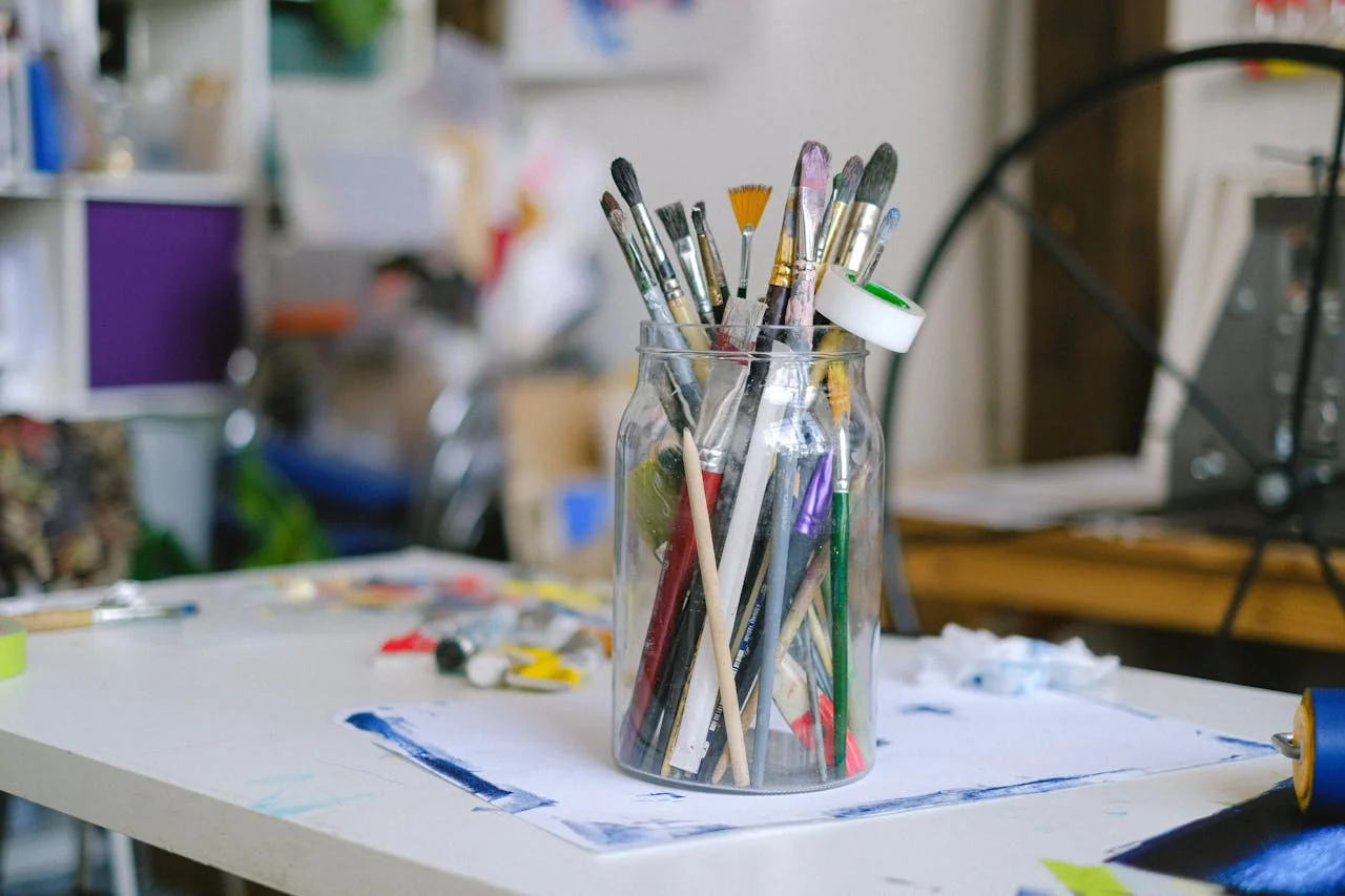 Pot rempli de pinceaux et matériel de peinture dans un atelier créatif