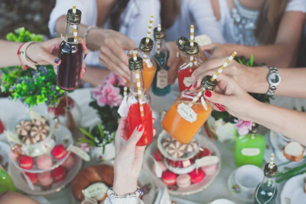 amis trinquant avec des bouteilles colorées lors d’un brunch festif 