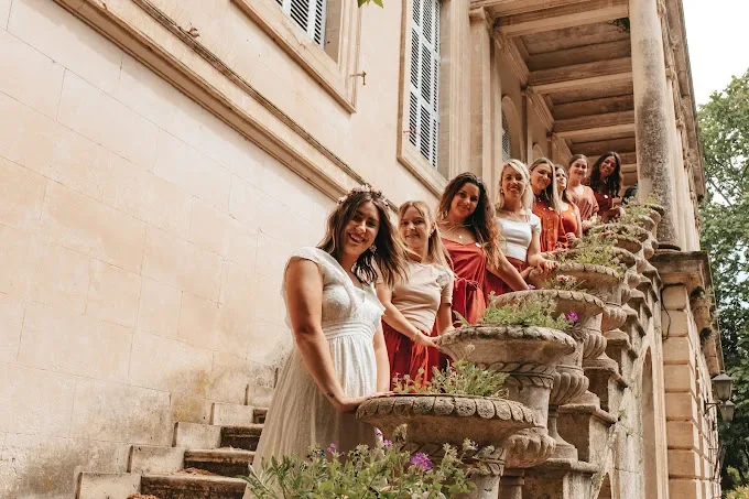 groupe de femmes en tenue d evjf posant sur un escalier ancien à montpellier devant un bâtiment en pierre claire
