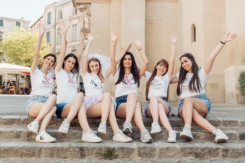 groupe d’amies assises sur des marches levant les bras en l’air pendant un evjf à montpellier