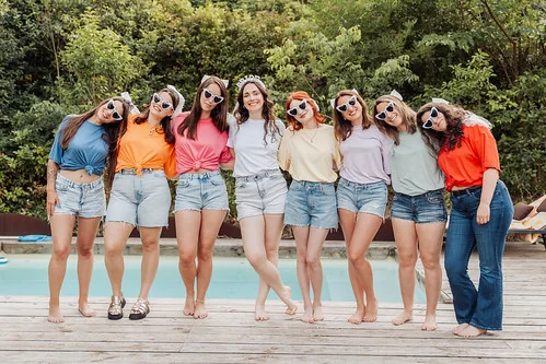 groupe d’amies en tenue colorée posant ensemble près d’une piscine 