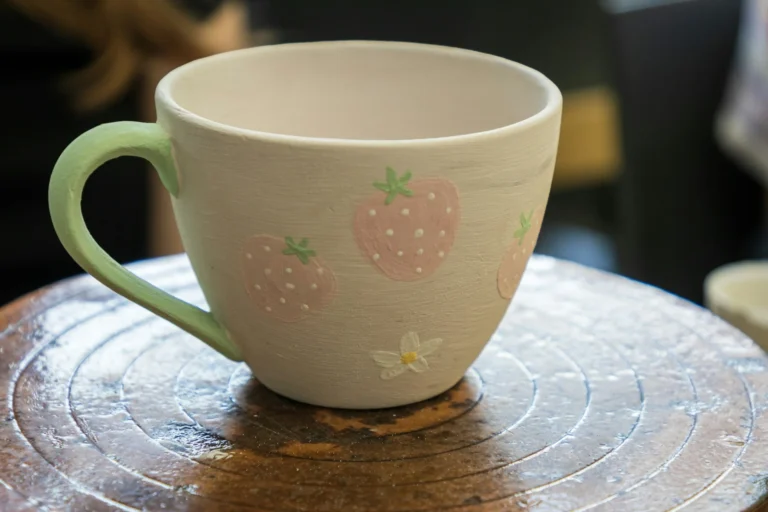 Tasse en céramique décorée de motifs de fraises, réalisée pendant un atelier peinture.