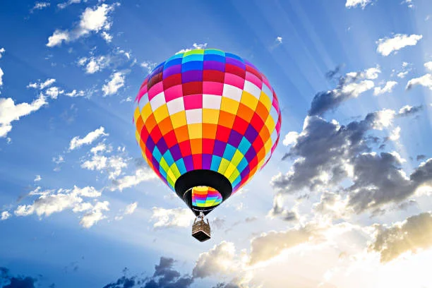 Montgolfière colorée s’élevant dans le ciel au lever du soleil, symbole d’un vol en montgolfière