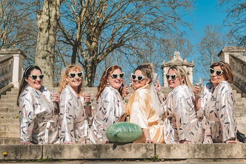 groupe de femmes en peignoirs et lunettes coeur posant sur des marches