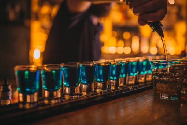 alignement de shots bleus servis sur un comptoir de bar a dijon pendant un evjf avant de decouvrir les 10 bars pour sortir a dijon pendant un evjf