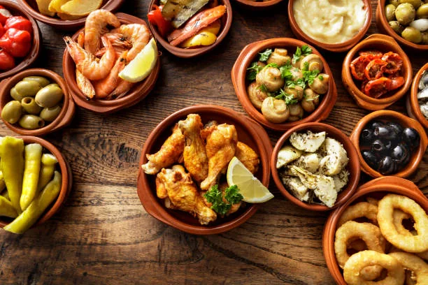 assortiment de tapas avec crevettes olives et ailes de poulet sur une table en bois dans un bar a dijon pendant un evjf avant de decouvrir les 10 bars pour sortir a dijon pendant un evjf