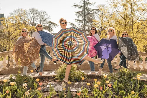 Groupe d’amies posant avec des parapluies colorés dans un jardin de Dijon, illustrant l’article 10 bonnes raisons de faire un EVJF à Dijon