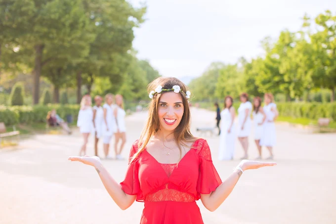 femme en robe rouge souriante devant un groupe d amies en robes blanches pendant un evjf a paris