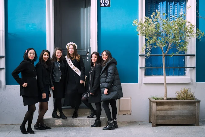 groupe de femmes en noir posant devant une maison bleue pendant un evjf a paris