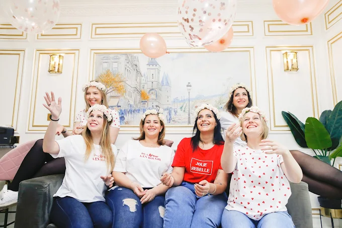 groupe de femmes souriantes jetant des ballons pendant un shooting evjf a paris dans un interieur chic