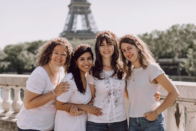 groupe de femmes souriantes portant des couronnes de fleurs devant la tour eiffel pendant un evjf a paris