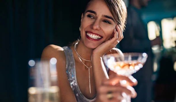 femme souriante tenant un cocktail dans un bar chic pendant un evjf a nantes pour illustrer les 10 endroits ou sortir a nantes pendant un evjf