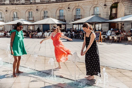 trois femmes jouant dans une fontaine sur une place ensoleillee a dijon illustrant les 10 idees originales pour un evjf a dijon