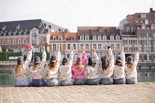groupe de femmes assises au bord de l eau levant les bras pendant un evjf a lille