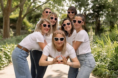 groupe de femmes portant des lunettes en forme de coeur posant dans un parc pendant un evjf a lille