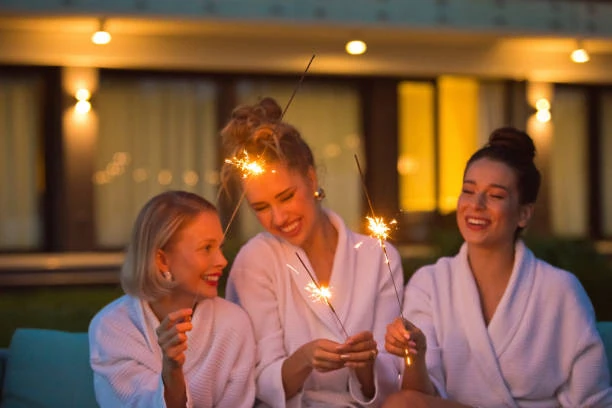 trois femmes en peignoir rient avec des cierges magiques pendant un evjf a lille