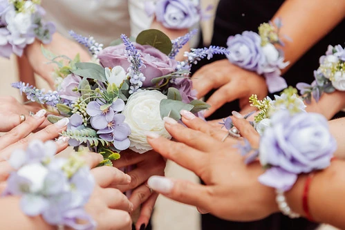 Mains de femmes autour d’un bouquet de fleurs violettes pendant un atelier floral d’EVJF à Nantes