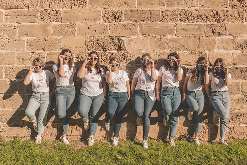 Groupe de femmes en tenue assortie posant devant un mur en pierre 