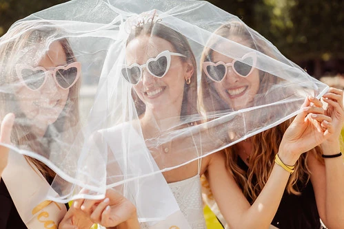 Trois femmes portant des lunettes en forme de cœur et un voile de mariée 