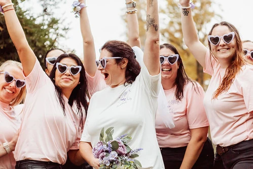 Groupe de femmes en t-shirts roses célébrant un EVJF à Nantes avec la mariée tenant un bouquet de fleurs
