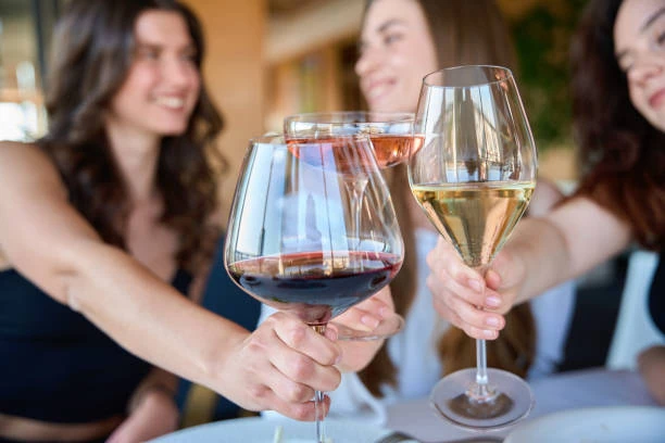 trois femmes trinquant avec des verres de vin lors dun diner evjf a paris