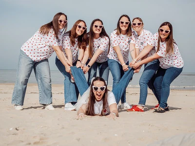 groupe de personne entrain de faire du paddle groupe d’amies s’amusant sur la plage en tirant la mariée allongée lors d’un evjf au touquet paris plage